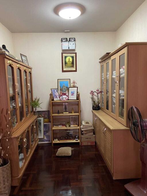 A cozy living room with wooden cabinets and a shelf displaying various items