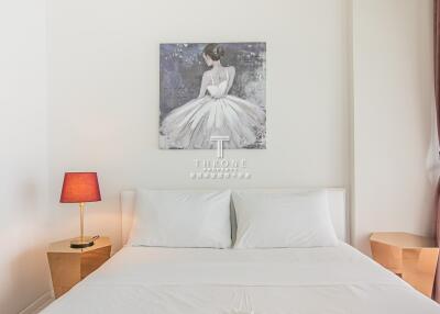 Cozy modern bedroom with white sheets, bedside tables, a lamp, and a wall picture