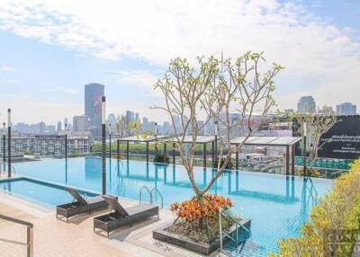 Rooftop swimming pool with lounge chairs and city skyline view