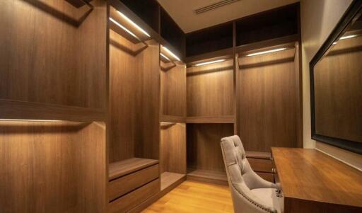 Spacious wooden walk-in closet with seating