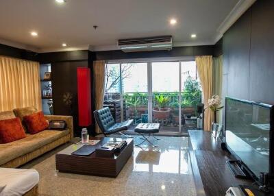 Modern living room with comfortable seating, large TV, and balcony access.
