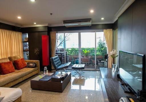 Modern living room with comfortable seating, large TV, and balcony access.