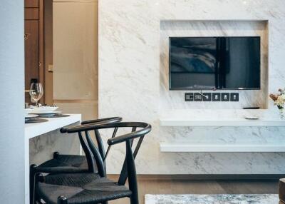 Modern living area with chairs, dining table, TV, and marble wall