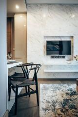 Modern living area with chairs, dining table, TV, and marble wall