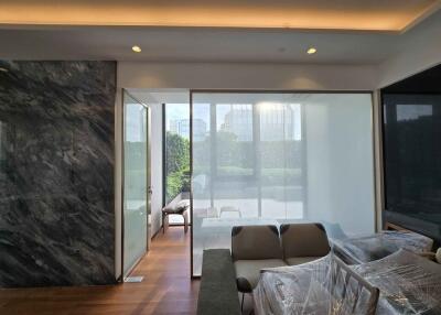 Modern living room with marble wall, floor-to-ceiling windows, and contemporary furniture