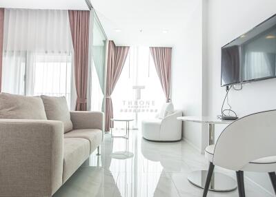 Modern living room with sofa, chair, TV, and large windows