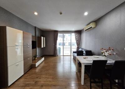 Modern living room with wooden flooring, dining table, and balcony access