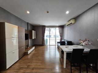 Modern living room with wooden flooring, dining table, and balcony access