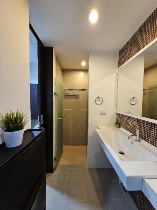 Modern bathroom with tiled walls, glass shower, and a white sink