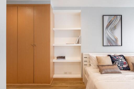 Modern bedroom with wooden wardrobe, bed with pillows and wall art.