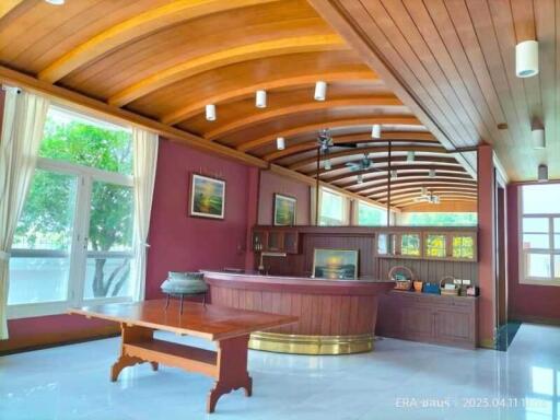 Spacious well-lit main living area with wooden ceiling and large windows