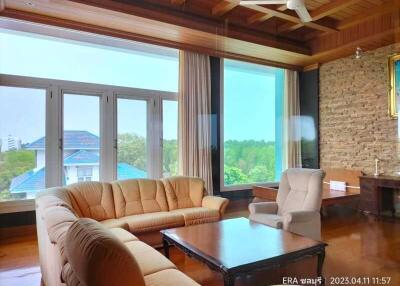 Spacious living room with large windows, comfortable seating, and a wooden ceiling.
