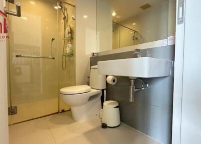 Modern bathroom with glass shower, toilet, and wall-mounted sink