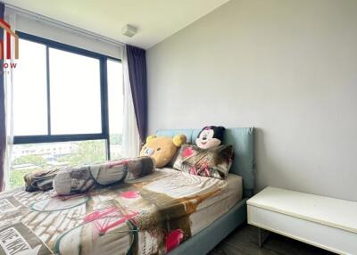 Bedroom with large window and stuffed toys on bed