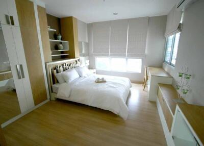 Modern bedroom with wooden flooring, white bedding, and ample storage