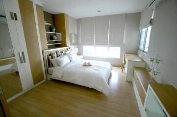 Modern bedroom with wooden flooring, white bedding, and ample storage