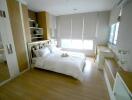 Modern bedroom with wooden flooring, white bedding, and ample storage