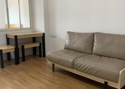 Minimalist living room with a brown leather sofa and a small wooden table with chairs