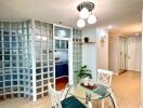 Modern dining area with a glass table and chairs, adjacent to the kitchen with glass block wall partition