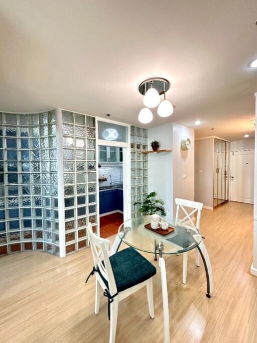 Modern dining area with a glass table and chairs, adjacent to the kitchen with glass block wall partition