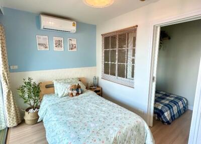 Cozy bedroom with double bed, air conditioning unit, and window to a small adjacent room