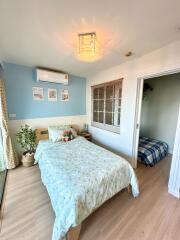 Cozy bedroom with double bed, air conditioning unit, and window to a small adjacent room