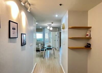 Bright hallway with light wooden flooring and decorative wall art leading to an open living area