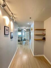 Bright hallway with light wooden flooring and decorative wall art leading to an open living area