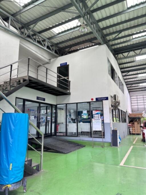 Exterior view of an industrial building with a staircase and a green floor