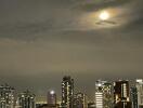 Night view of city skyline with illuminated buildings and a cloudy sky