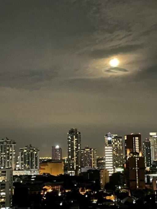 Night view of city skyline with illuminated buildings and a cloudy sky