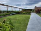 Rooftop garden with green lawn, pathway, and seating area