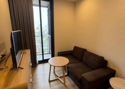 Modern living room with brown sofa, wooden flooring, TV unit, and balcony access