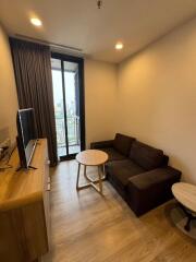 Modern living room with brown sofa, wooden flooring, TV unit, and balcony access