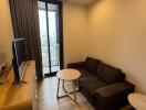 Modern living room with brown sofa, wooden flooring, TV unit, and balcony access