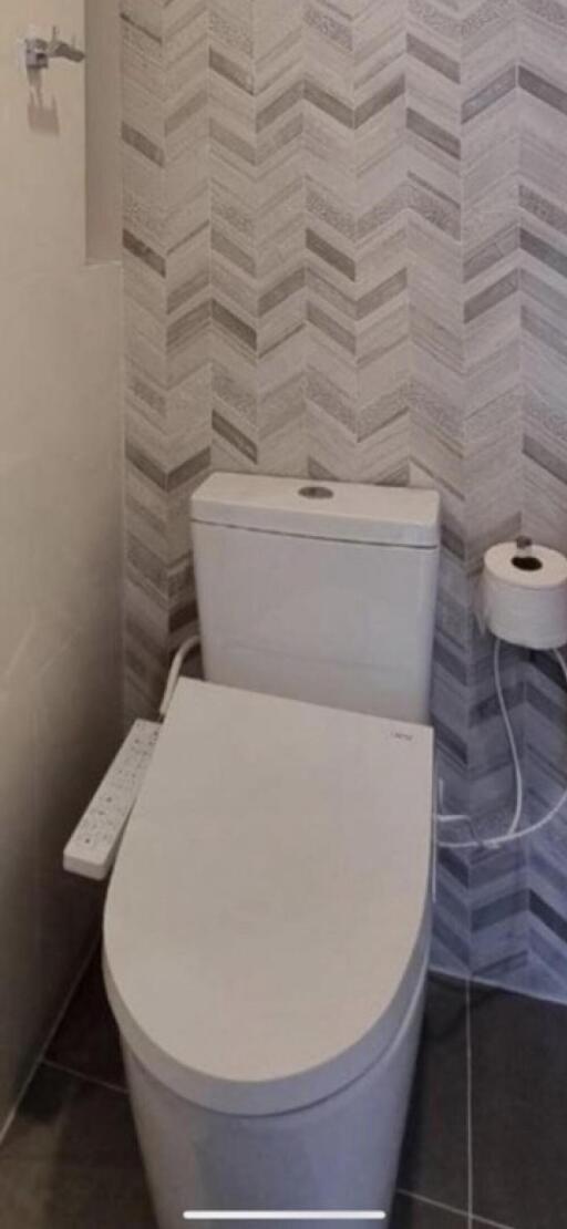 Modern bathroom with a herringbone tile pattern and a sleek toilet