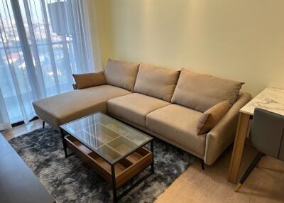 Modern living room with beige sectional sofa and glass coffee table