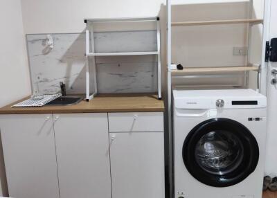 Laundry area with washing machine, sink, and shelves