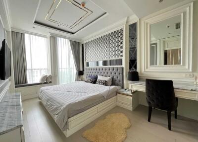 Modern bedroom with large windows, bed, desk and seating area