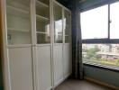 Bedroom with white storage cabinets and a large window