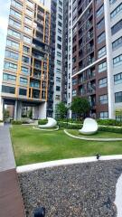 Exterior view of modern high-rise residential buildings with landscaped greenery and unique outdoor seating.