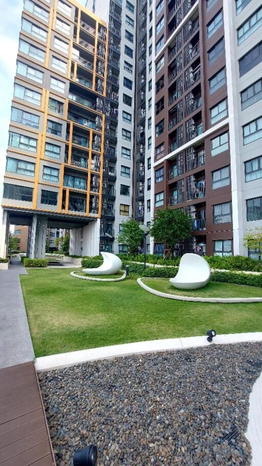 Exterior view of modern high-rise residential buildings with landscaped greenery and unique outdoor seating.