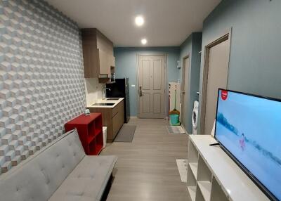 Modern living space with TV, couch, and kitchenette