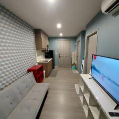 Modern living space with TV, couch, and kitchenette