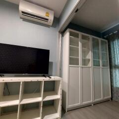 Living room with air conditioner, TV, shelving unit, and glass cabinet