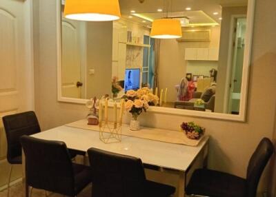 Modern dining area with seating for four, featuring a large wall mirror and decorative lighting