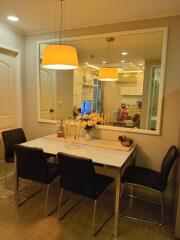 Modern dining area with seating for four, featuring a large wall mirror and decorative lighting