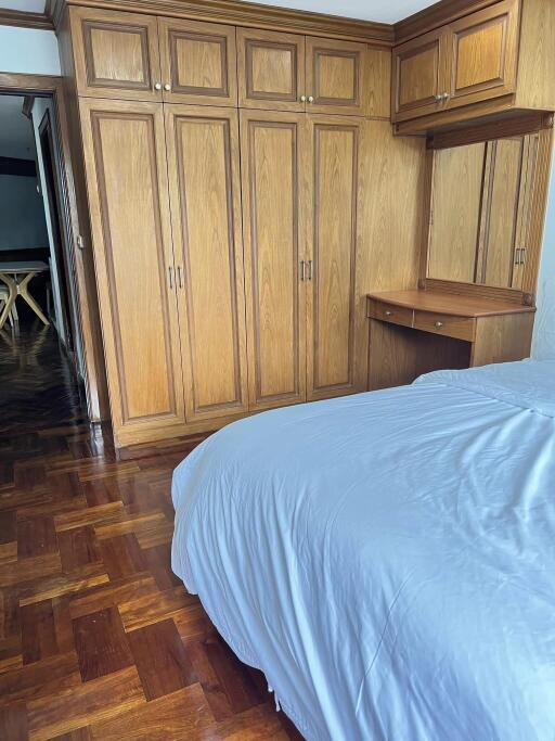 Bedroom with wooden built-in wardrobes and a bed with a blue cover