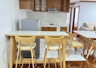 Open kitchen area with wooden cabinets and bar stools