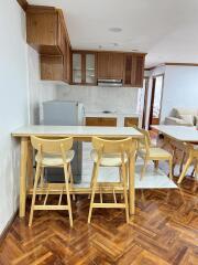 Open kitchen area with wooden cabinets and bar stools